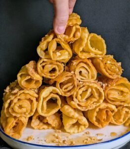 diples displayed on a blue and white plate served with walnuts, honey, and cinnamon
